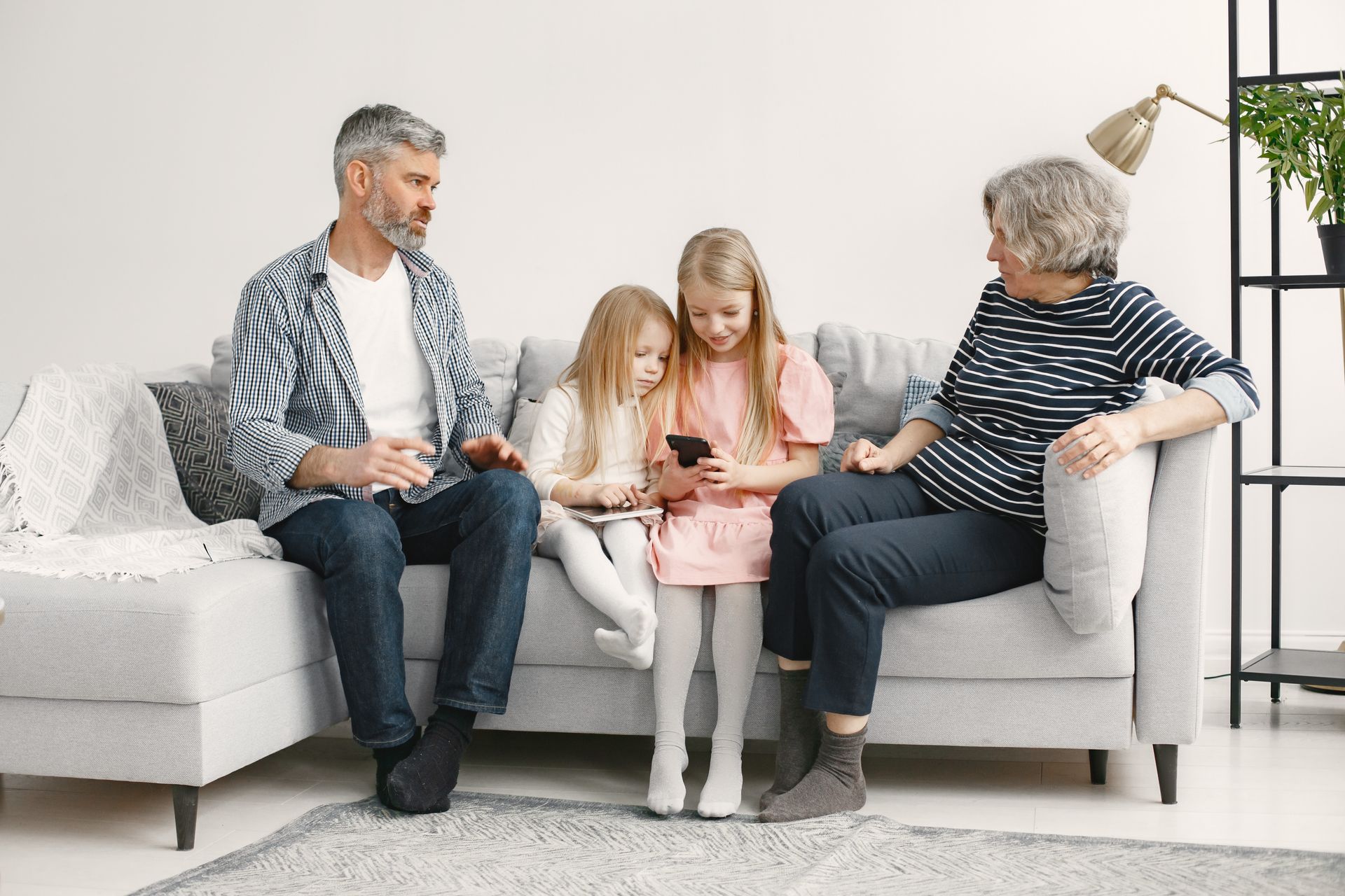 Grandfather and grandmother on a sofa with two young grandchildren looking at a tablet